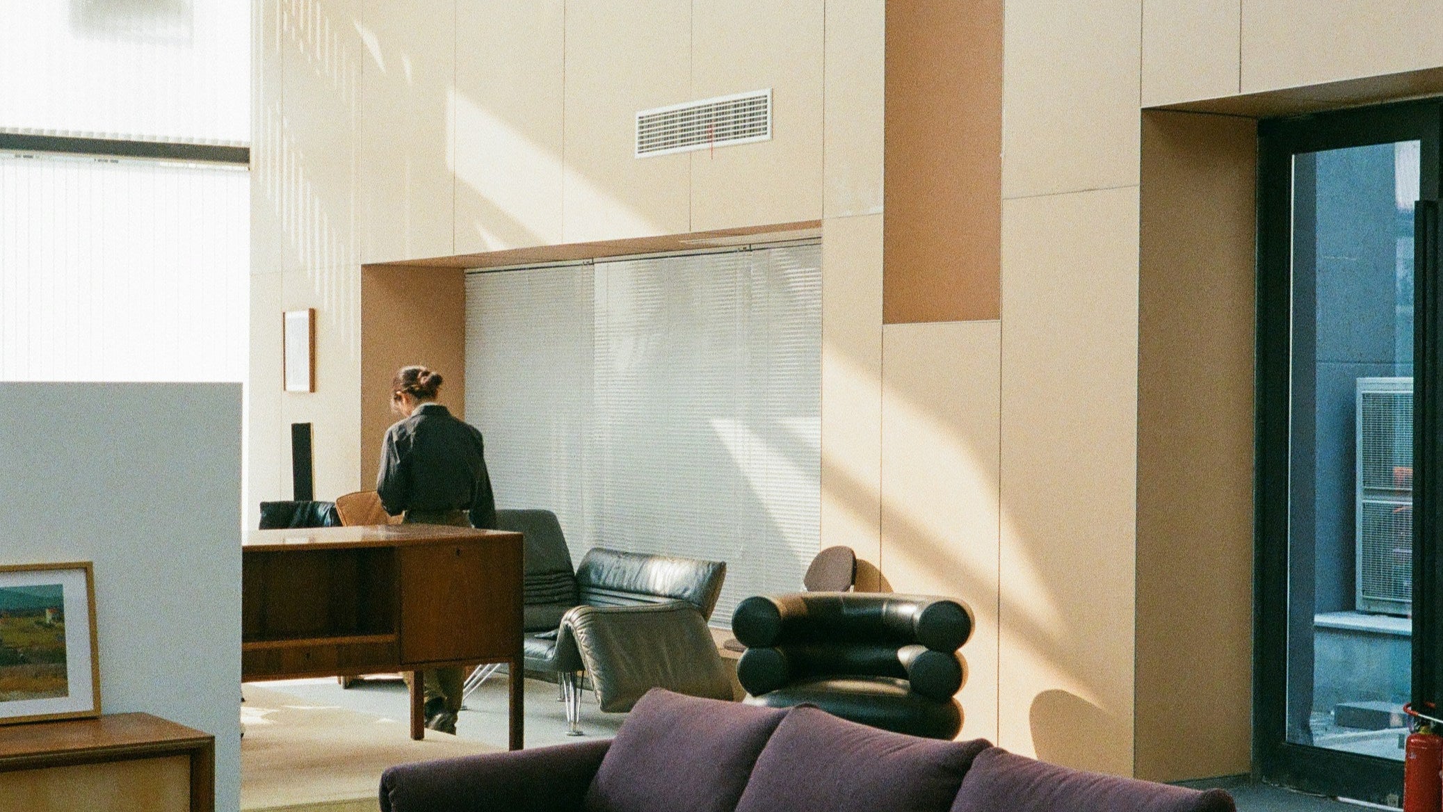 Modern interior with a purple sofa, wooden coffee table, and large windows.